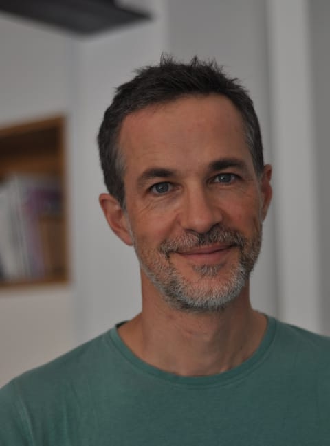 Portrait de Benoit Marini, de face, souriant, tee-shirt vert
