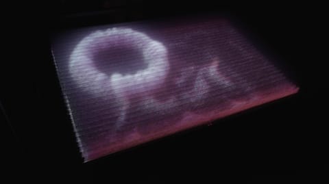 Turbulence : une forme de lumière blanche et rose, comme une volute, flotte dans l'obscurité